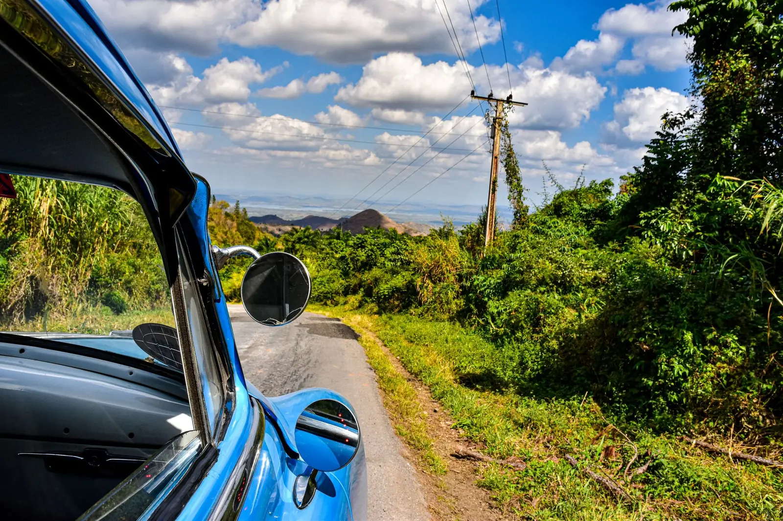Old car on a rural road surrounded by vegetation