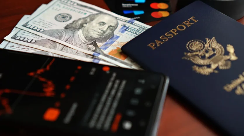 Banknotes, cards and a passport laid out on a table before a trip
