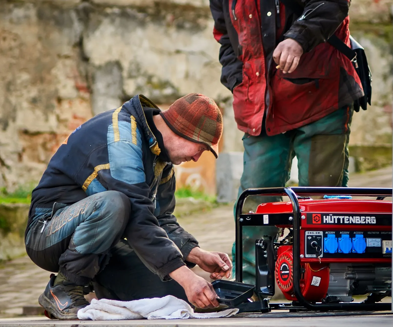 Two technicians checking a portable electric generator outdoors