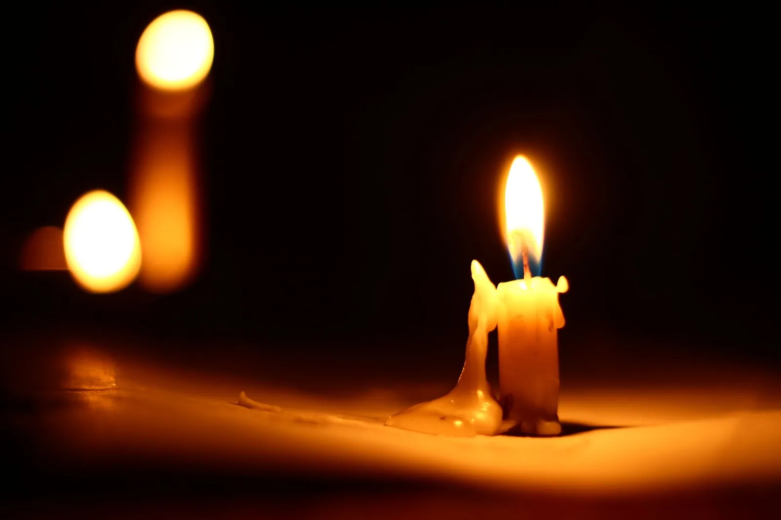 A lit candle against a dark background