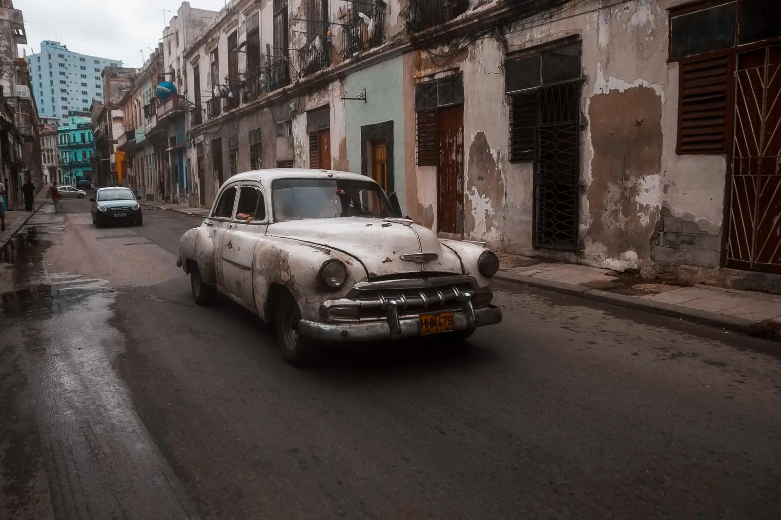 Coche clásico circulando por una calle de una ciudad cubana