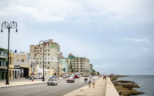 Street along the Malecón in Havana with classic cars and the sea behind