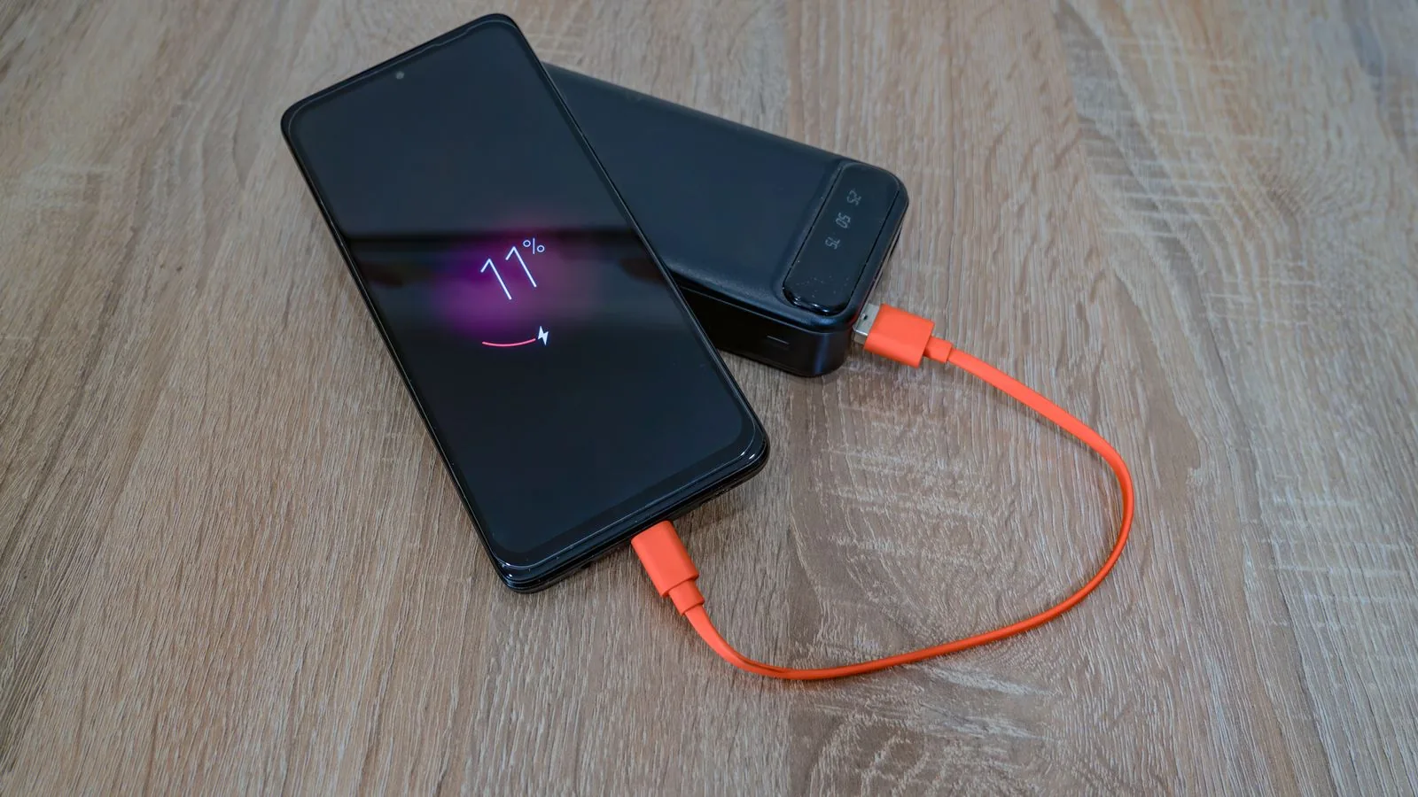Teléfono móvil cargándose con una batería externa sobre una mesa de madera
