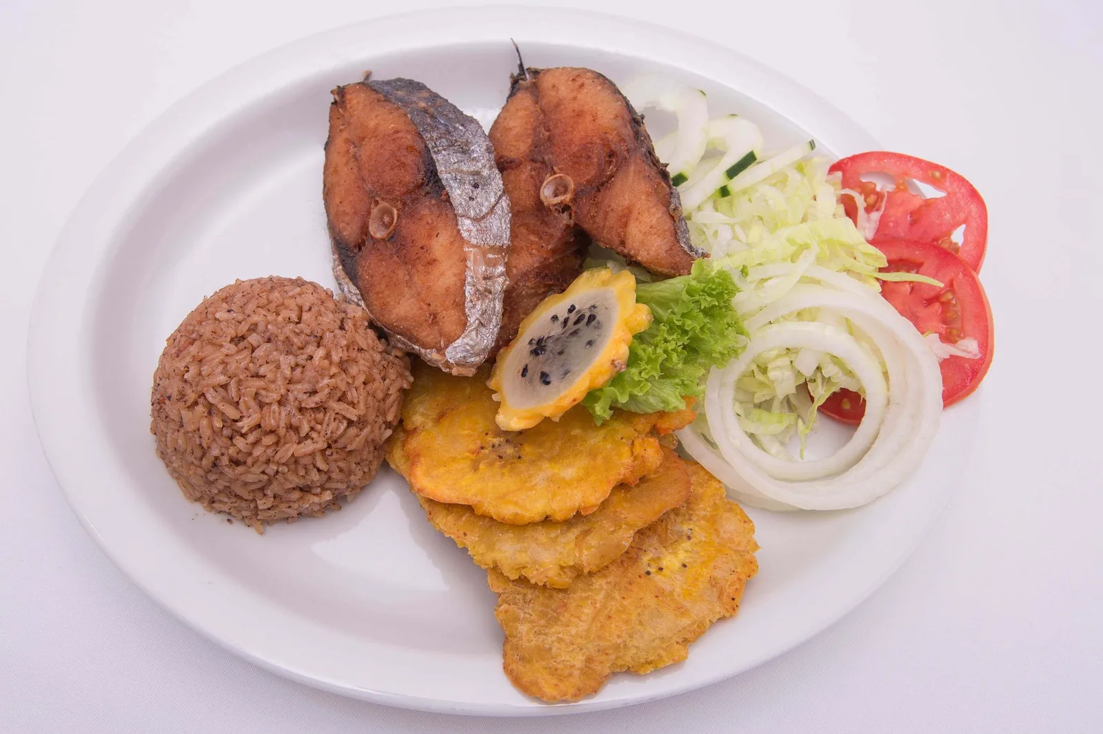 Plato de pescado frito con arroz, plátano y ensalada